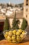 Glass bowl with green andalusian olives served on outdoor terrace with view on old part of Granada, Andalusia, Spain