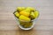 Glass bowl of pickled yellow jalapeno peppers on wooden table, closeup