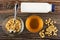 Glass bowl with puffed wheat, spoon, bottle of yogurt, honey, scattered puffed wheat on table. Top view