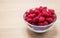 Glass bowl of red raspberries isolated on a wooden counter