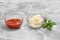 Glass bowls with ketchup and cheese sauce on kitchen table.