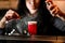 Glass with bright red cocktail which woman bartender sprinkles and decorates