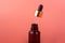 glass brown bottle with pipette with essential oil on a pink background top view. Aromatic cosmetic product for skin and hair care