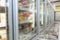 Glass cabinets with refrigerated food in the supermarket. Side view. Blurred