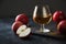 Glass with Calvados brandy and red apples on black.