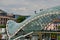 Glass canopy of pedestrian Bridge of Peace over Kura River cleaned by cleaners on harness Tbilisi Georgia