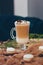 A glass of cappuccino with marshmallow on the brown cloth with macaroons, cinnamon sticks in Christmas atmosphere