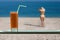 A glass of carrot juice with a straw in the cafe. Female in the bikini and straw hat on the beach