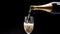 Glass of champagne being filled from a bottle with dark background