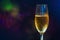 A glass of champagne on the right side of the frame on a multi-colored blurry background