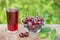 A glass of cherry juice and bowl of cherries on the table in garden outdoors