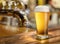 Glass of chilled beer on wooden bar table top and blurred bar interior at the background