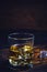 Glass chilled whiskey with ice cubes on wooden background in cellar