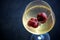 Glass of chilled white wine with strawberries on blue pool water background