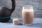 Glass of Chocolate Protein Shake with milk and banana, Whey protein in scoop and black sporting kettlebell in background. Sport nu