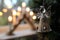 Glass Christmas tree decoration hanging near a window with a traditional candle arch or bridge in blurred background