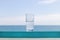 Glass of clean cool water against the background of the sea