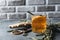 glass clear Cup of fruit tea with cinnamon stick, rosemary, ginger, dried orange slice on grey background