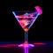 Glass of cocktail in hypnotic neon light. Colorful rave party drink. Selective focus