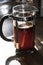 Glass coffee cafetiere also known as a french press filled with freshly brewed black coffee grounds on a kitchen counter
