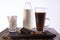 A glass of coffee with chocolate on a tray, a bottle of milk and bags with sugar in the background on a white background