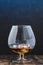 Glass of cognac with ice cubes on a wooden bar/Glass of cognac with ice cubes on a wooden bar with bleu light background