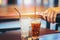 Glass of cola splashing with ice on wooden table background