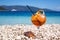 Glass of cold aperol-spritz cocktail on the white pebbles of the amazing Antisamos beach, Kefalonia island, Greece.