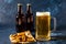 Glass of cold beer and botle chips on wooden table