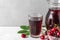 Glass of cold cherry juice with a jug and fresh berries on white background. Refreshment summer drink