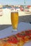 Glass of cold draft beer and pizza toast with blurry sunny Copacabana beach of Rio de Janeiro, Brazil in Background