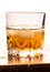 Glass of cold whiskey on wooden surface