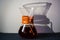 Glass container filled with black coffee on one-ton white background with reflection of large and unusual shadows.