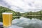 Glass of cool wheat light beer with lake background