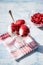 Glass creamer with ice cream balls and jam from red cranberries on a red napkin, berries in focus, blue background.