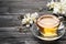 Glass cup of aromatic jasmine tea and fresh flowers on black wooden table, space for text