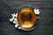 Glass cup of aromatic jasmine tea and fresh flowers on black wooden table, top view