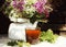 glass cup black tea green leaf berry white kettle table sunlight close-up summer outdoor bouquet flowers