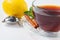 A glass cup with black tea on a saucer with mint, cinnamon and lemon, and a tea strainer.