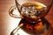 Glass cup with black tea on the sunny brown table. Closeup view with amazing light and shadow