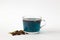 Glass cup of blue herbal tea on a white background