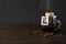 Glass cup with drip coffee bag and beans on black wooden table. Space for text