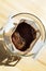 Glass cup with drip coffee bag on wooden table closeup. Instant paper macro sachet above. Fresh morning making coffee