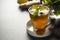 Glass cup of ginger tea with lemons and mint leaves on dark background. Ginger tea, drink ingredients, cold and autumn time