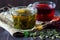 Glass cup of green herbal hot tea and cup of red hibiscus tea with dry leaves with fresh green leaves of mint.