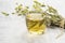 Glass cup of herbal sage tea with dried sage leaves on white wooden rustic background