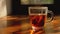 Glass cup of hot tea with teabag vaporing on table in sunrise light