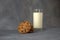 Glass cup with milk and several oatmeal cookies on a gray abstract background. Close-up