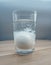 Glass cup with mineral water and an egg inside. The egg is dipped inside the glass and is enveloped in a white consistency. Close-