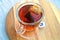 Glass cup, mug of red colored, hot Rooibos or red bush tea, on a wooden plate, aromatic drink, beverage, tonic, stimulant